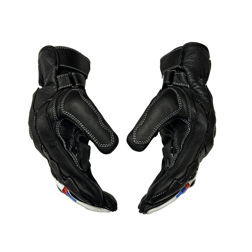 A pair of black leather motorcycle gloves shown from the back, featuring white contrast stitching and small red and blue accents near the wrist, set against a plain white background.