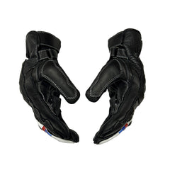 A pair of black leather motorcycle gloves shown from the back, featuring white contrast stitching and small red and blue accents near the wrist, set against a plain white background.