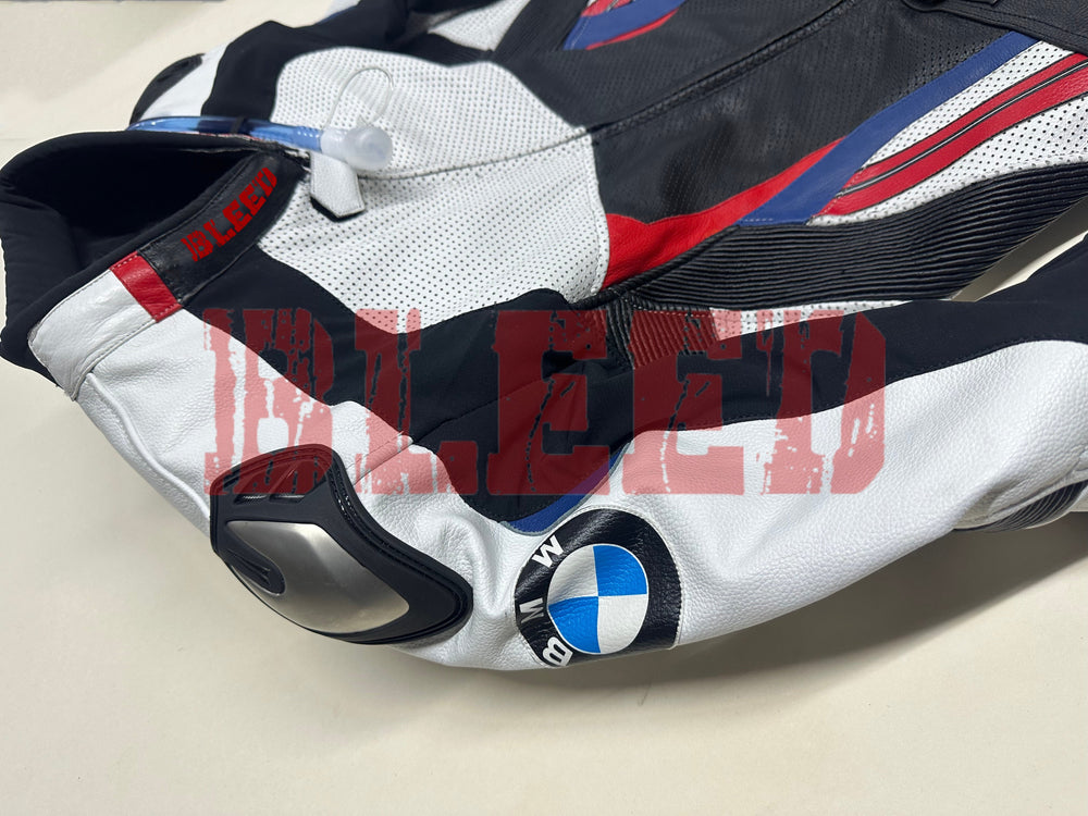 Side view of the BMW Double R Men's Motorbike Race Suit, showcasing the white sleeve with the BMW logo and integrated shoulder protection. The suit features black, red, and blue accents, emphasizing its sporty and protective design tailored for high-performance riding